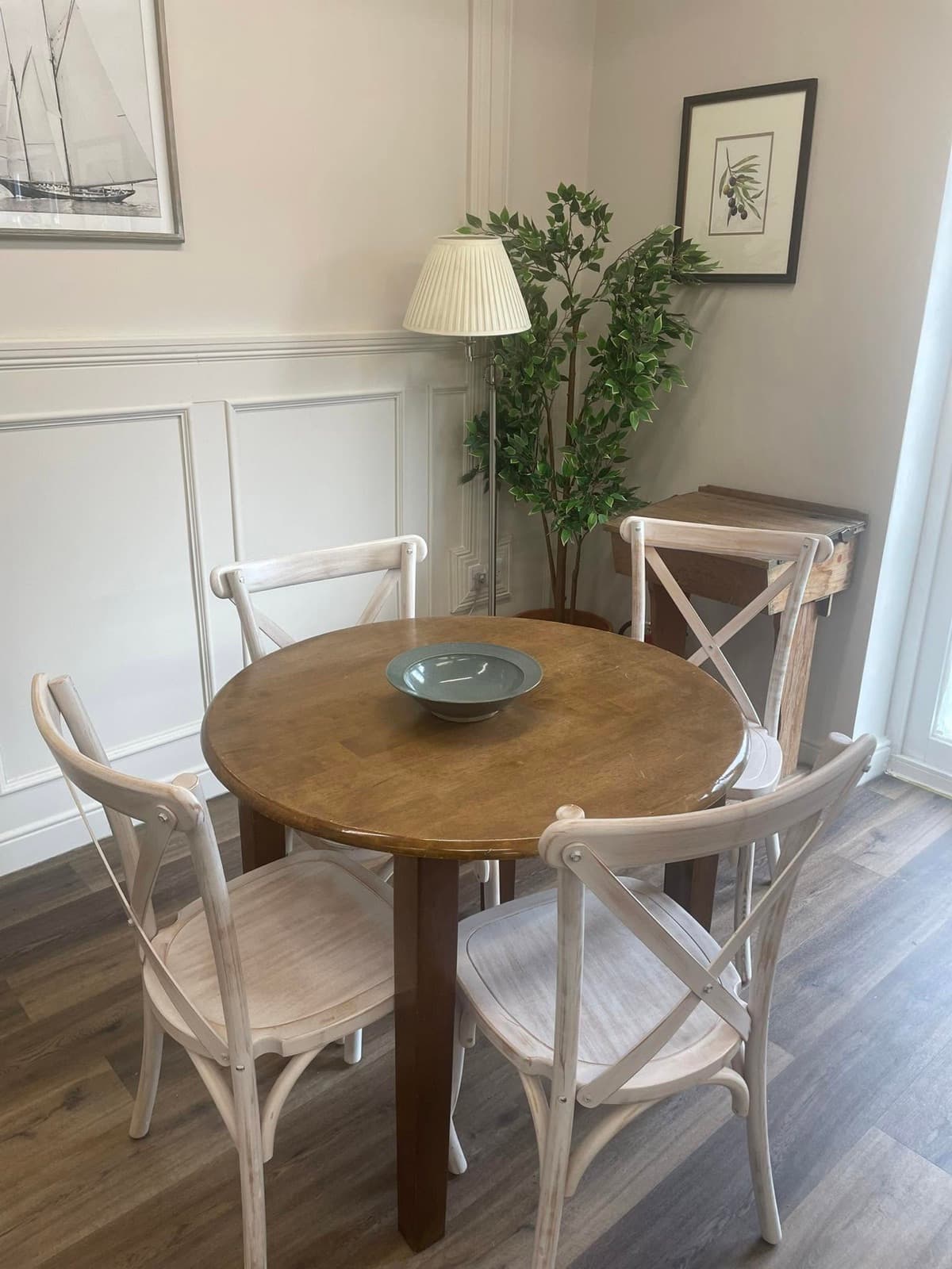 A corner table at The Olive Tree with whitewashed cross-back chairs and panelled walls